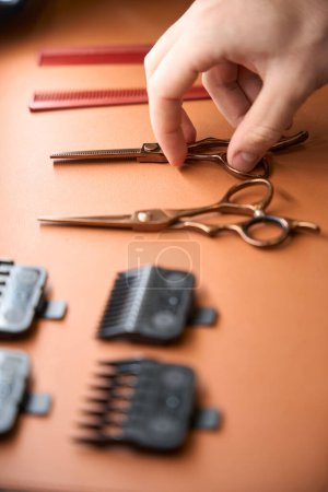 Téléchargez les photos : Coiffeur non identifié prenant des ciseaux de coiffeur dans le salon de coiffure - en image libre de droit