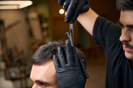 Foto de Peluquero experto con tijeras de empuñadura elaboración de corte de pelo elegante para su cliente en la barbería - Imagen libre de derechos
