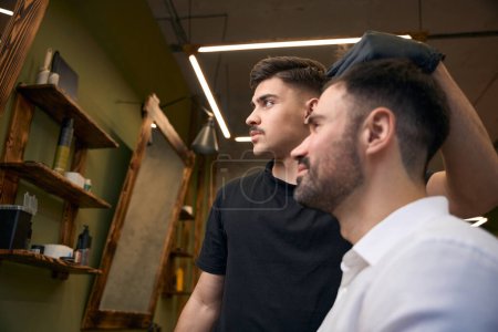 Téléchargez les photos : Guy se faire coiffer par un coiffeur professionnel dans un salon de coiffure - en image libre de droit