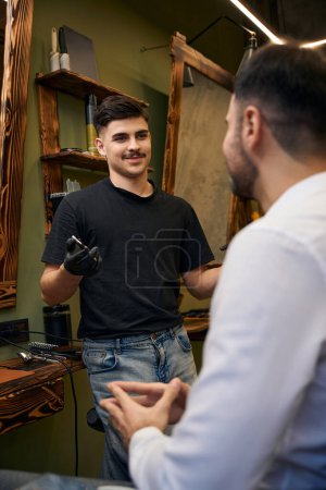 Téléchargez les photos : Coiffeur homme faisant coiffure élégante fournissant un service professionnel pour le coiffeur ion client - en image libre de droit