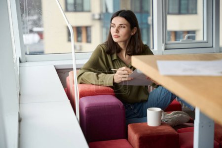 Téléchargez les photos : Pensive créatrice de vêtements femme penser à une nouvelle idée de travail dans le café - en image libre de droit