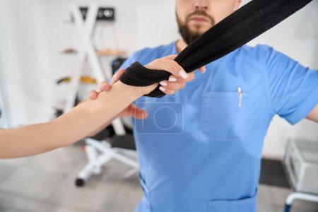 Photo for Woman does stretching exercises under the supervision of a kinesiologist using a special device - Royalty Free Image