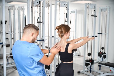 Téléchargez les photos : Physiothérapeute surveille les exercices d'un jeune patient, les cours ont lieu dans la salle de gym - en image libre de droit
