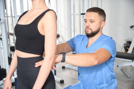 Téléchargez les photos : Chiropraticien forme posture correcte pour un jeune patient, les cours ont lieu dans la salle de gym - en image libre de droit