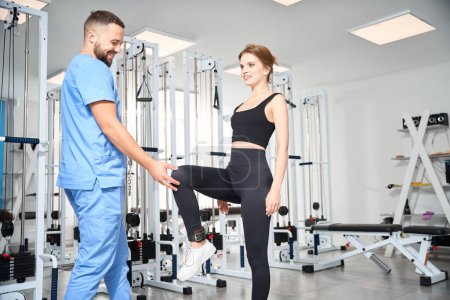 Foto de Las formas fisioterapeuta postura correcta para una paciente femenina, las clases tienen lugar en el gimnasio - Imagen libre de derechos