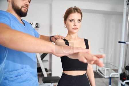 Téléchargez les photos : Médecin forme la posture correcte pour un jeune patient, les cours ont lieu dans la salle de gym - en image libre de droit