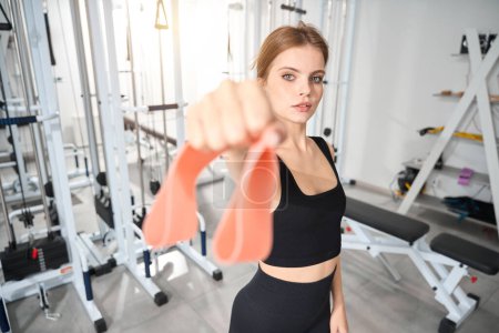 Photo for Young woman holds a fitness elastic band in her hand, female in a comfortable training suit - Royalty Free Image