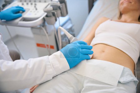 Téléchargez les photos : Spécialiste clinique mobile transducteur d'ultrasons sur l'abdomen du patient, effectuer des examens médicaux et des diagnostics dans l'hôpital moderne - en image libre de droit