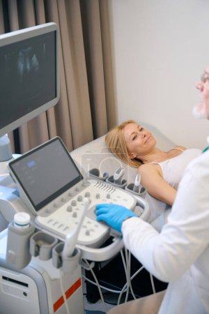 Foto de Transductor de ultrasonido móvil masculino clínico en el abdomen del paciente, realización de examen médico y diagnóstico en el hospital moderno - Imagen libre de derechos