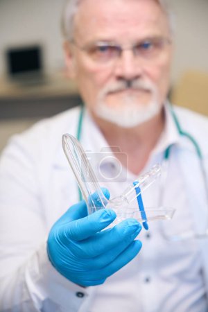 Foto de Ginecólogo profesional en guantes azules que sostiene el espéculo ginecológico y listo para el examen del paciente - Imagen libre de derechos