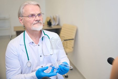 Foto de Médico profesional en guantes azules que sostiene el espéculo ginecológico y listo para el examen del paciente - Imagen libre de derechos