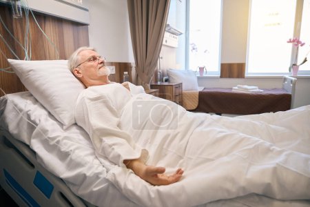 Photo for Portrait of adult man patient lying on hospital bed and recovering after having surgery - Royalty Free Image