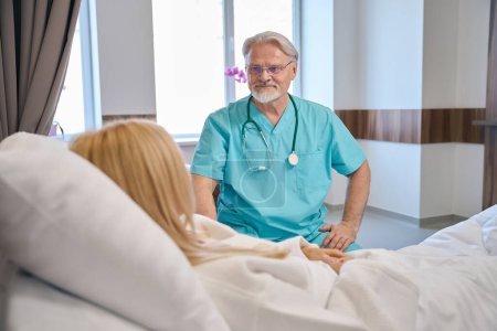 Foto de Médico o médico consultando a una mujer bonita mientras se recupera después de una cirugía exitosa descansando en la cama médica - Imagen libre de derechos