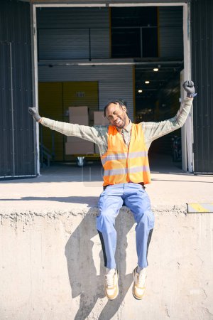 Tired loader stretching while sitting outdoors on loading dock in front of storehouse building