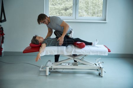 Physiotherapist works on the spine of an elderly lady, the woman lies on a special massage table