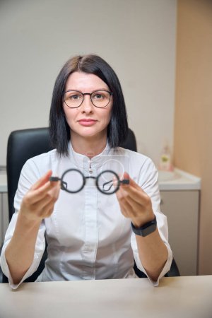 La mujer lleva gafas especiales en las manos, un médico con uniforme blanco