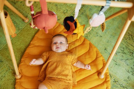 Photo for Adorable little baby playing with wooden baby gym - Royalty Free Image