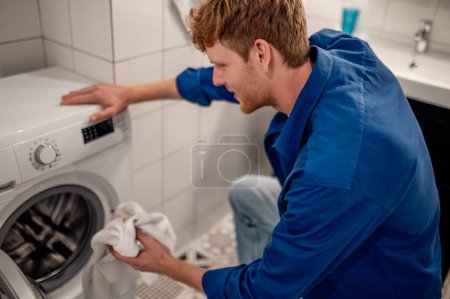 Foto de Lavado necesario. Hombre poniendo clolthes no frescos en la lavadora - Imagen libre de derechos