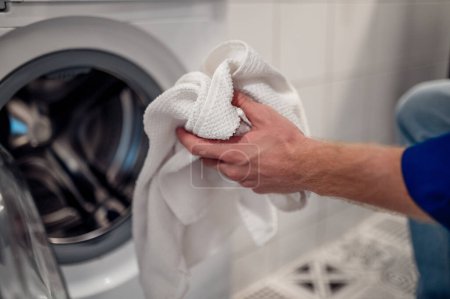 Foto de Lavado necesario. Hombre poniendo clolthes no frescos en la lavadora - Imagen libre de derechos