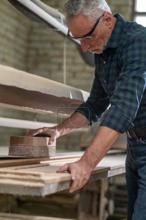 Photo for Carpenter at work. Carpenter hewing the wood and looking involved - Royalty Free Image
