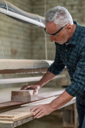 Photo for Carpenter at work. Carpenter hewing the wood and looking involved - Royalty Free Image