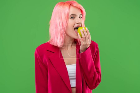 Foto de Retrato en la cintura de una chica hambrienta con un piercing en la lengua y frenos mordiendo una manzana verde ante la cámara - Imagen libre de derechos