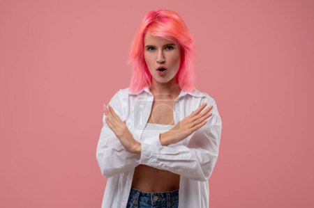 Foto de Retrato de cintura hacia arriba de una joven mujer decidida de moda con cabello rosa que demuestra un gesto de rechazo - Imagen libre de derechos