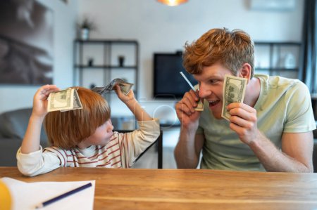 Foto de Educación financiera. Papá enseñando a su pequeño hijo los fundamentos financieros - Imagen libre de derechos