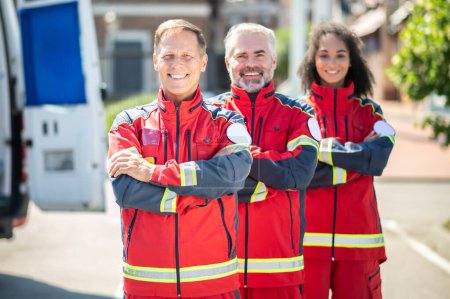 Téléchargez les photos : Équipe de professionnels paramédicaux confiants et joyeux debout à l'extérieur les bras croisés et regardant vers l'avenir - en image libre de droit