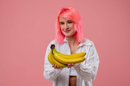 Foto de Retrato en la cintura de una linda chica con una sonrisa feliz sosteniendo un montón de plátanos en sus manos - Imagen libre de derechos