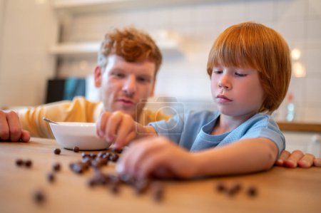 Photo for Playing before beakfast. Dad and son spending time together in the kitchen before breakfast - Royalty Free Image