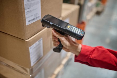 Cropped photo of an experienced storehouse worker hand directing a barcode reader at the cardboard box
