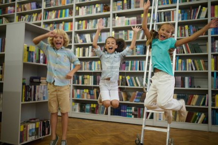 Glückliche Kinder. Gruppe süßer Kinder in der Bibliothek sieht glücklich und genussvoll aus