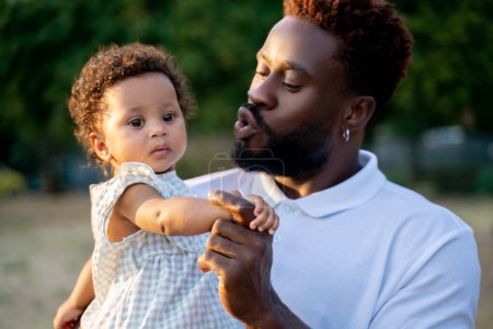 Photo for Loving young African American male parent talking to his cute little child in his arms - Royalty Free Image