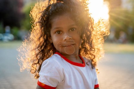 Photo for Portrait of a cute calm little African American girl posing for the camera on a sunny day - Royalty Free Image
