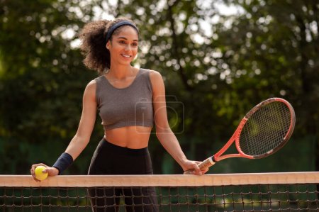 Foto de Pista de tenis. Sonriente linda chica morena con una raqueta en la corte - Imagen libre de derechos