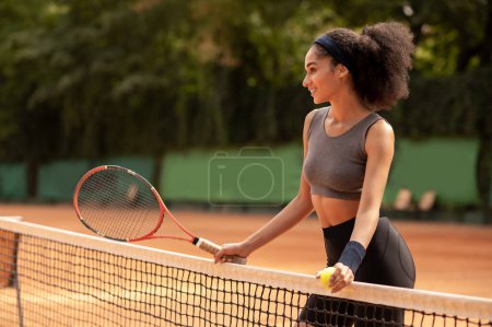 Téléchargez les photos : Terrain de tennis. Souriant jolie fille aux cheveux bruns avec une raquette à la cour - en image libre de droit