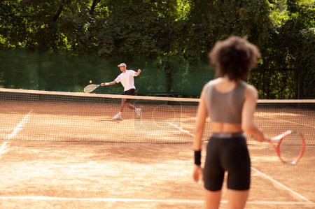 Foto de Jugando tenis. Dos jóvenes jugando al tenis y viéndose emocionados - Imagen libre de derechos