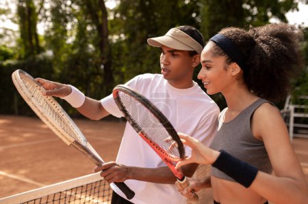 Entrenando. Entrenador masculino mostrando a la chica cómo sostener la raqueta de tenis