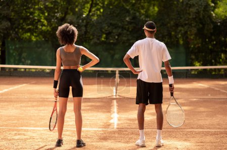 Foto de Entrenamiento. Dos jóvenes haciendo ejercicio en la cancha de tenis - Imagen libre de derechos