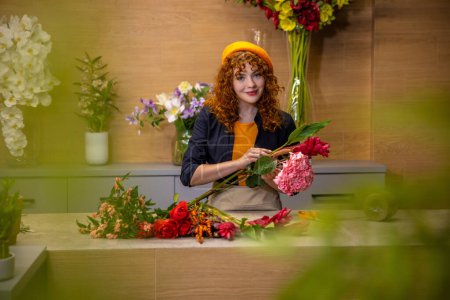 Foto de Florista en el trabajo. Floristería que elige flores para ramos en una tienda de flores - Imagen libre de derechos