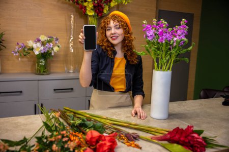 Photo for Flower shop. Young ginger girl in beret in a flower shop - Royalty Free Image