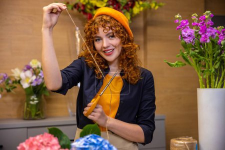 Photo for In a flower shop. Cute smiling girl with flowers looking enjoyed - Royalty Free Image