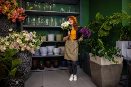Foto de En una florería. Linda chica sonriente con flores buscando disfrutado - Imagen libre de derechos