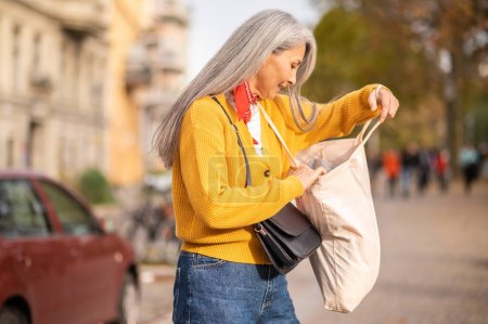 Foto de Después de comprar. Mujer con una bolsa de papel después de comprar en una calle de la ciudad - Imagen libre de derechos