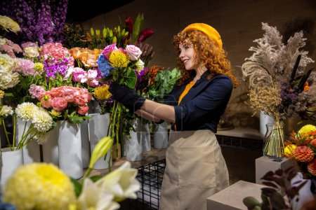 Téléchargez les photos : Beau fleuriste. Gingembre jeune femme dans un magasin de fleurs à la recherche romantique et satisfait - en image libre de droit