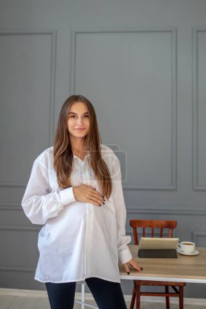 Photo for Working pregnant. Pretty long-haired pregnant woman at work in the office - Royalty Free Image