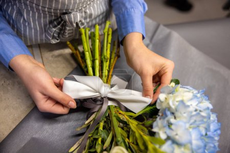 Photo for Flower shop. Close up of florist tying a ribbon on a bouquet - Royalty Free Image
