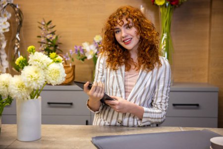 Photo for At the flower shop. Curly-haired florist at her working place - Royalty Free Image