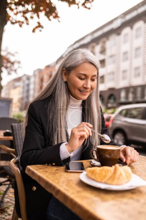 Téléchargez les photos : Dans un café de rue. Jolie femme aux cheveux longs déjeunant dans un café de rue - en image libre de droit